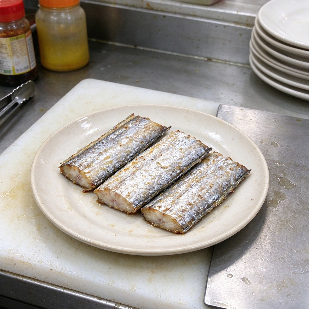 Silver beltfish segments arranged on a white plate