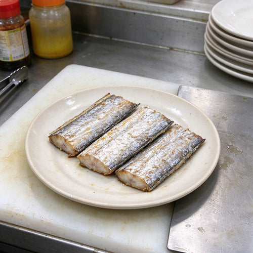 Silver beltfish segments arranged on a white plate